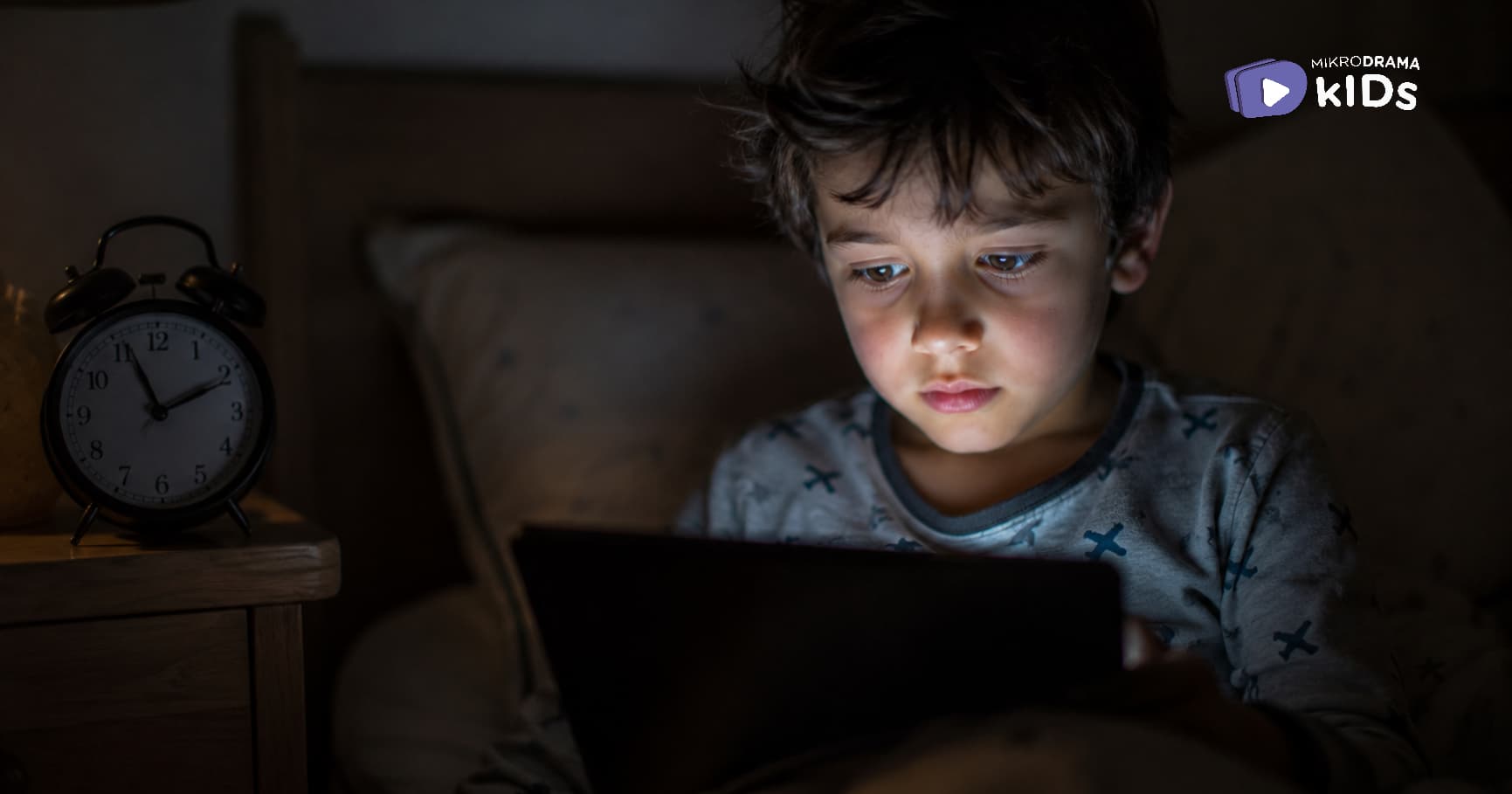 A boy looking at a tablet in the dark