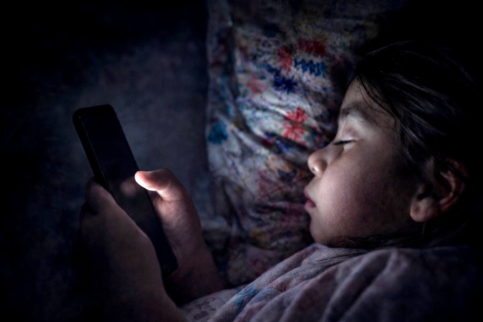 A girl scrolls her phone while sleeping