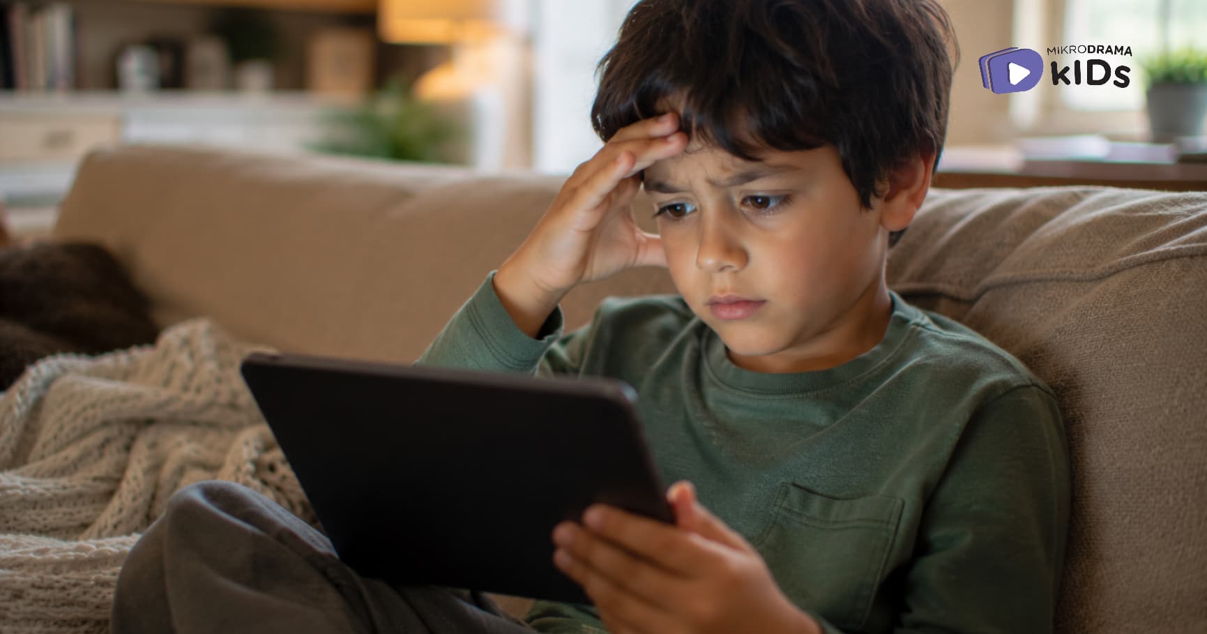 A boy looking at a tablet while holding his head